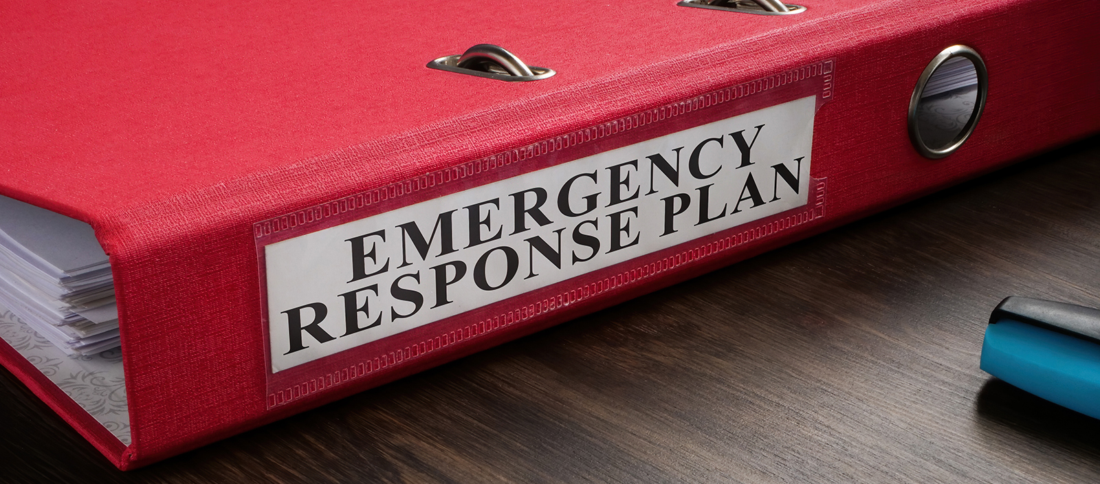 A red binder on a table with the sticker Emergency Response Plan.