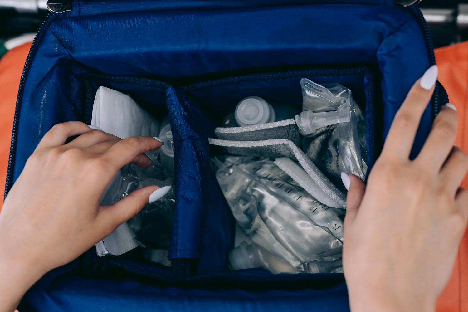 A photo of someone searching through items in a blue emergency kit.